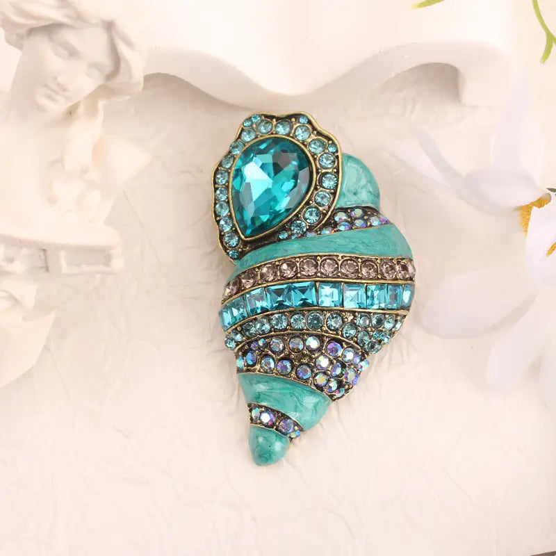 Broche conque vintage – Élégance en pierres précieuses bleues