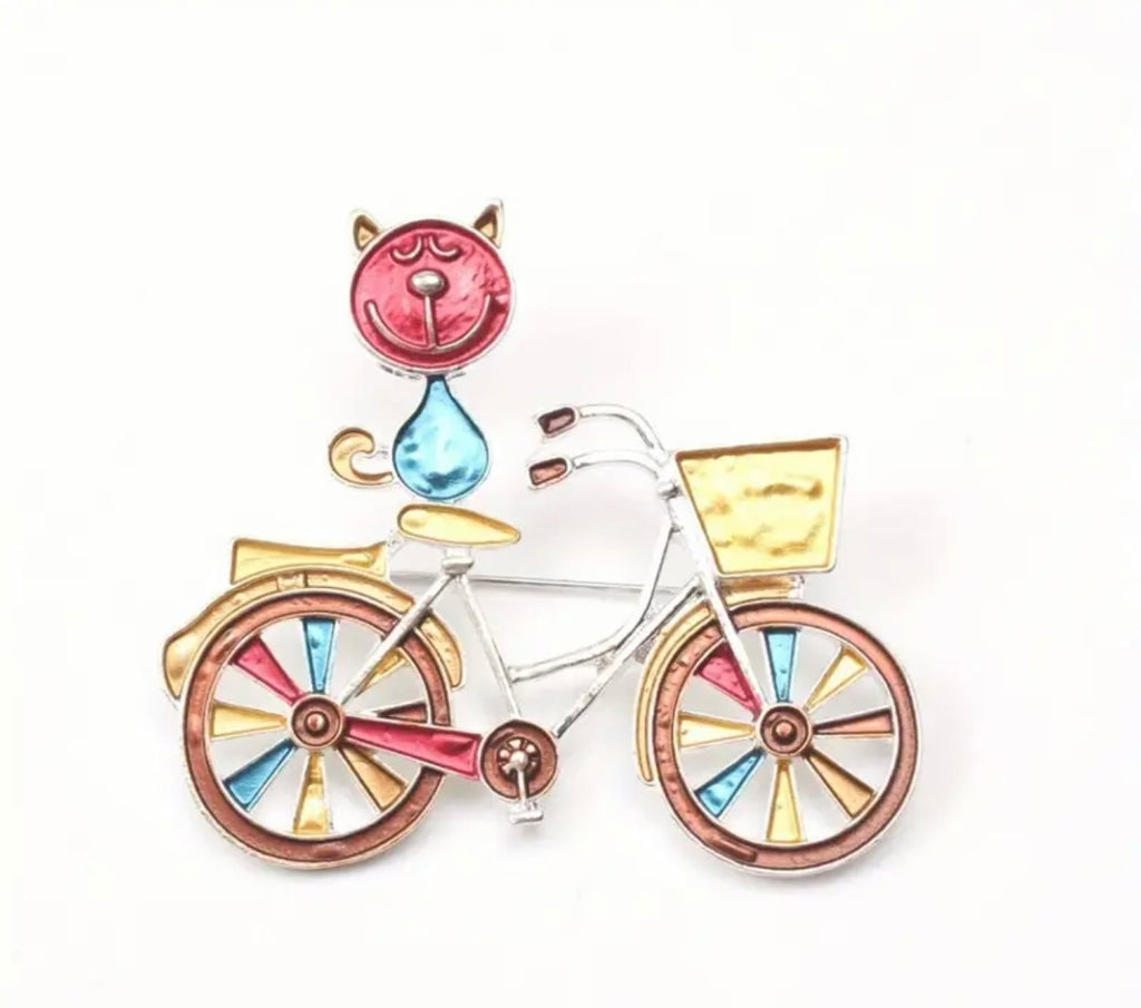 Broche élégante et colorée en émail représentant un chat sur un vélo