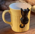 Chat suspendu sur une tasse à café