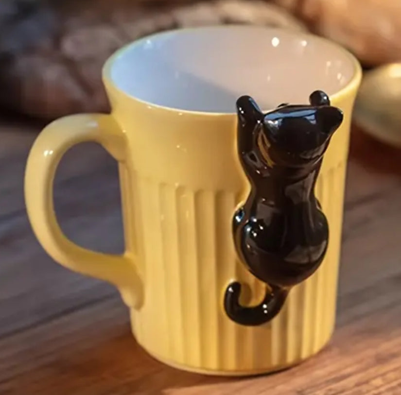 Chat suspendu sur une tasse à café