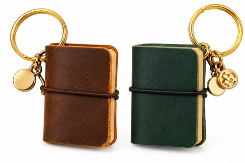 Brown and dark green genuine leather miniature notebook keychains on white background