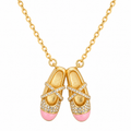 Gold-tone ballet shoes necklace with pink enamel toe caps on white background