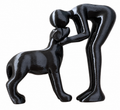 Black sculpture depicting a person affectionately greeting a dog