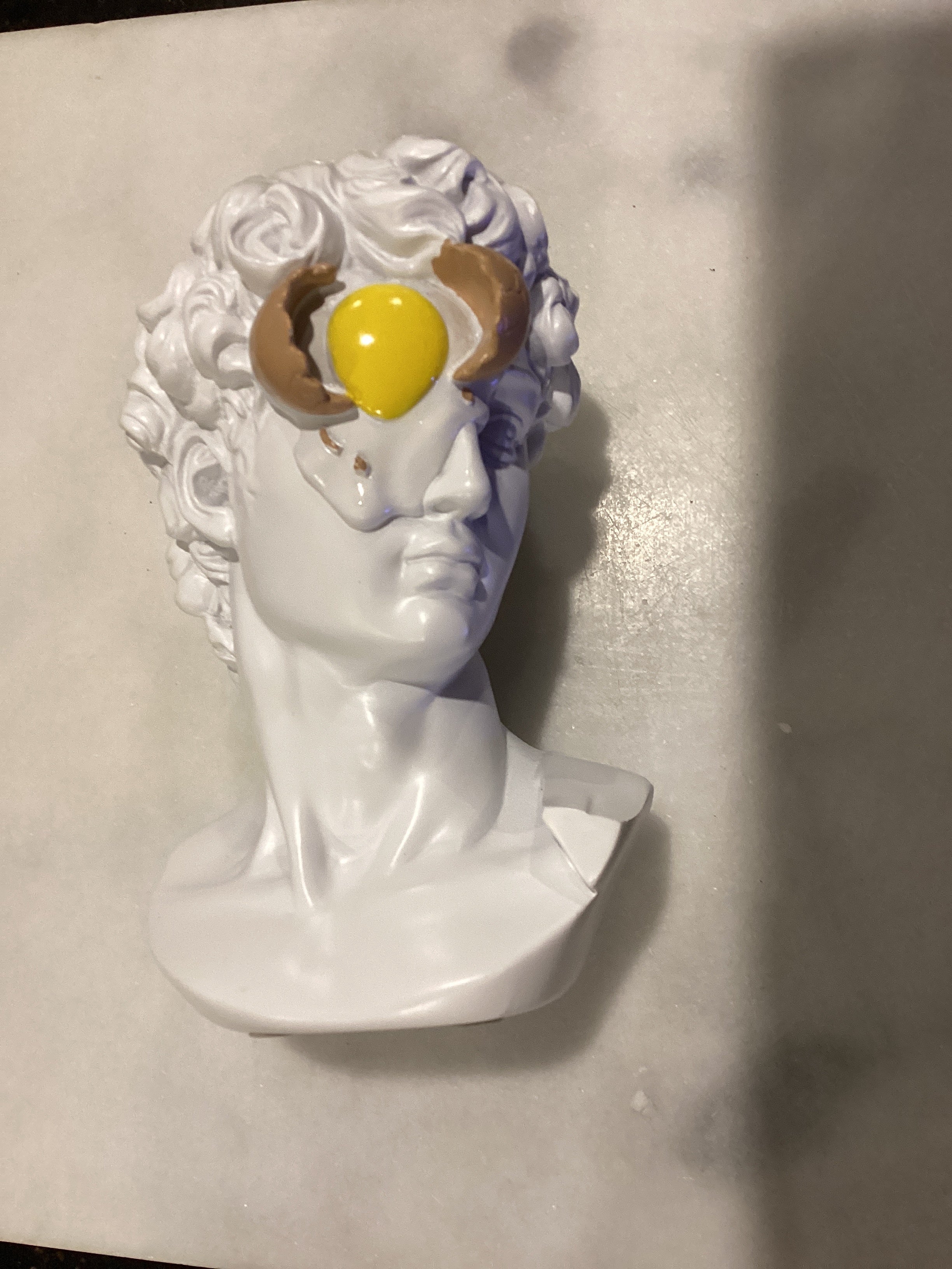 Statue d'un œuf sur le visage de David